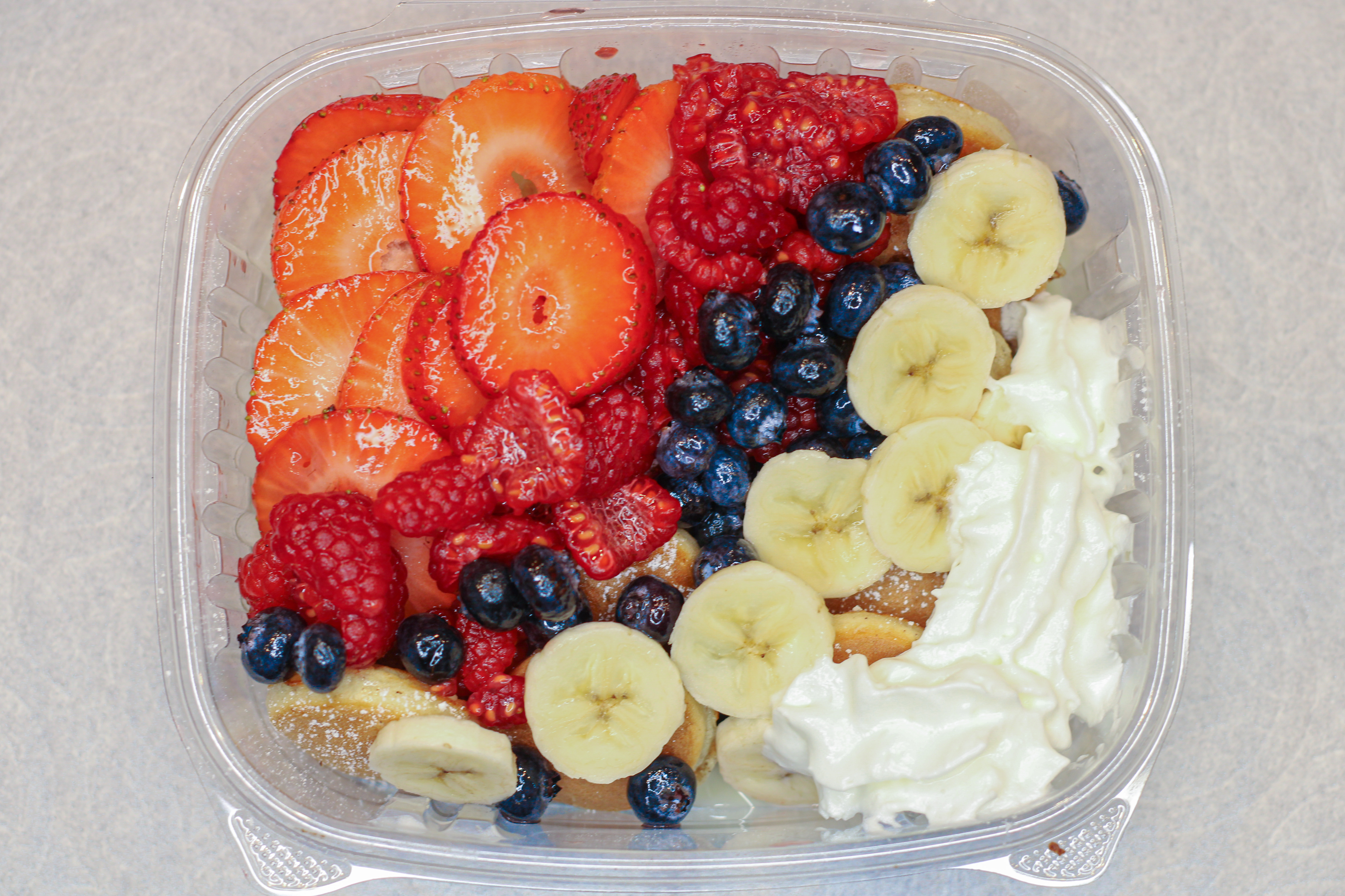 Pancakes with strawberries, blueberries, banana, and whipped cream